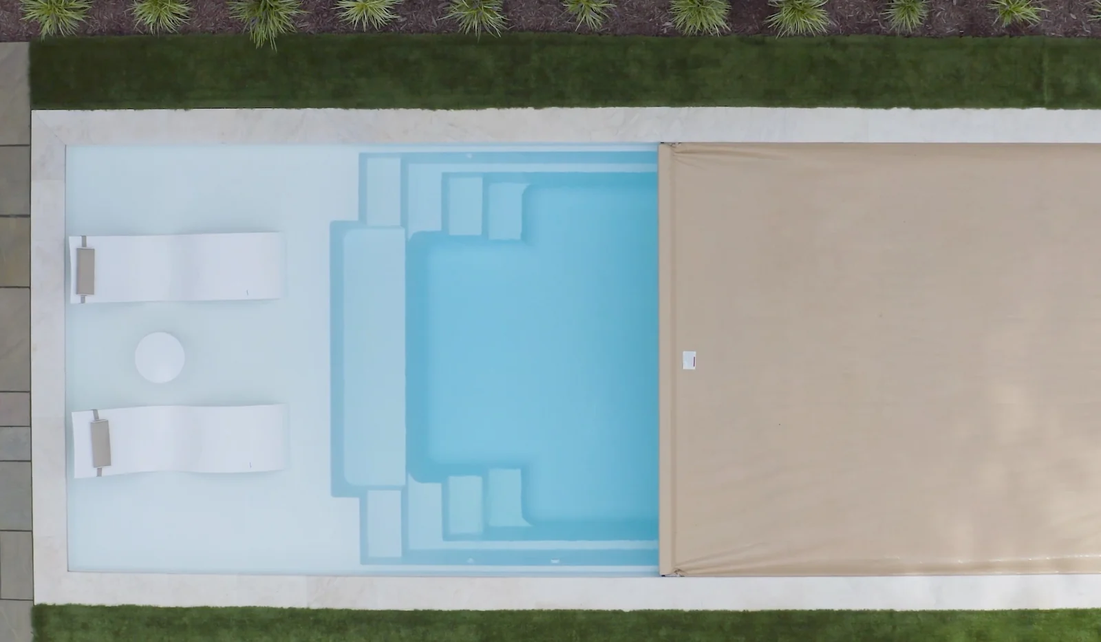Tan Integra automatic pool cover partially closing over an inground pool.