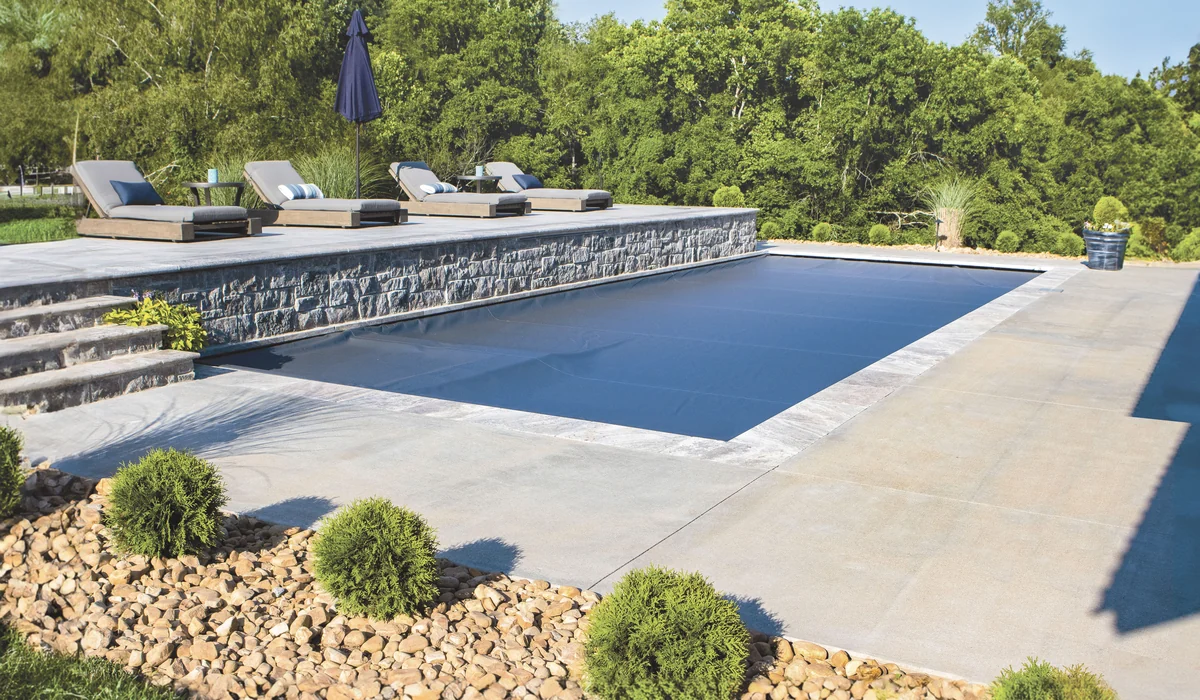 Closed Integra automatic pool cover keeping leaves and debris out of a backyard pool.
