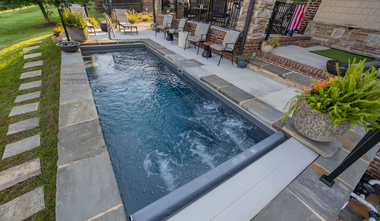 Integra automatic pool cover mechanism and track at the end of an inground pool.