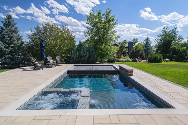 A landscaped backyard pool and raised spa with an Integra automatic cover at the far end.