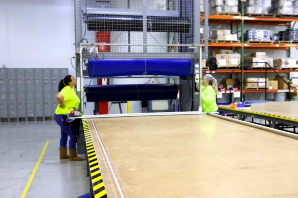 Two Integra Pool Covers team members beside fabric rollers and a production table