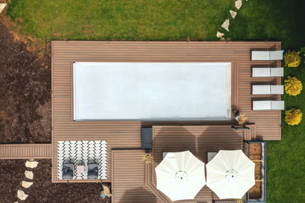 Aerial view of a light grey automatic cover closed over a pool within a landscaped deck